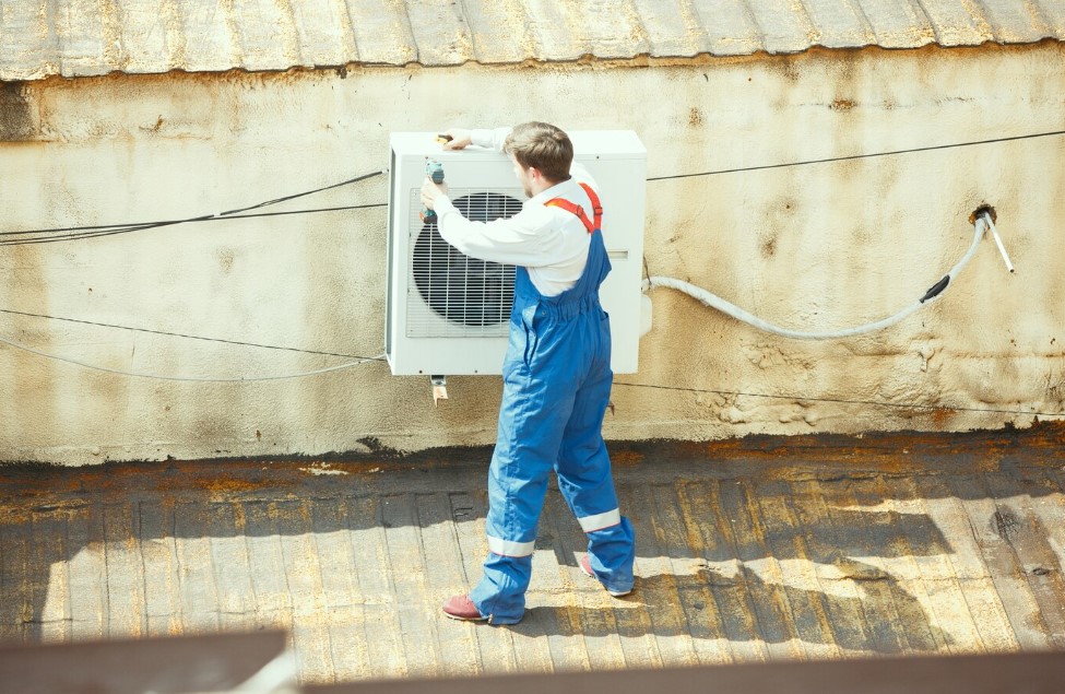 Instalador de aire acondicionado trabajando en la fachada de un edificio en Benidorm